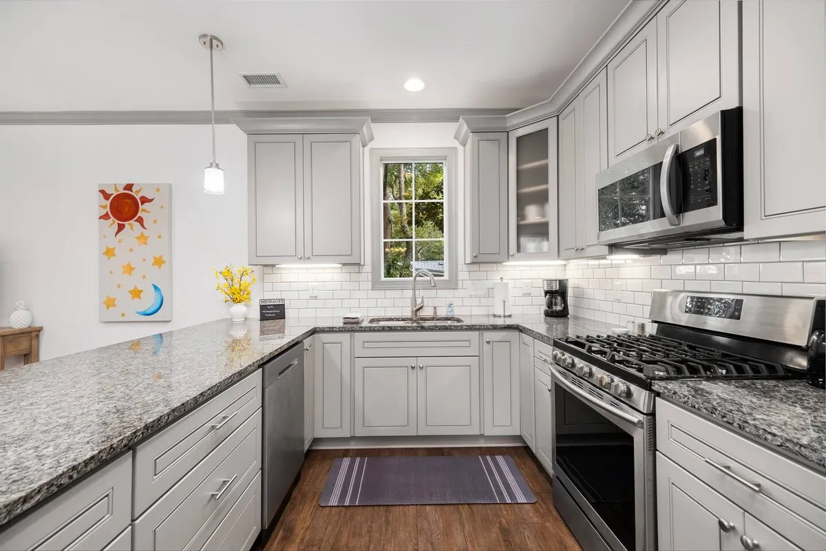 An inviting kitchen with granite countertops, stainless steel appliances, and decorative wall art. The natural light and open layout suggest a space that’s as suited for entertaining as it is for quiet culinary creativity.