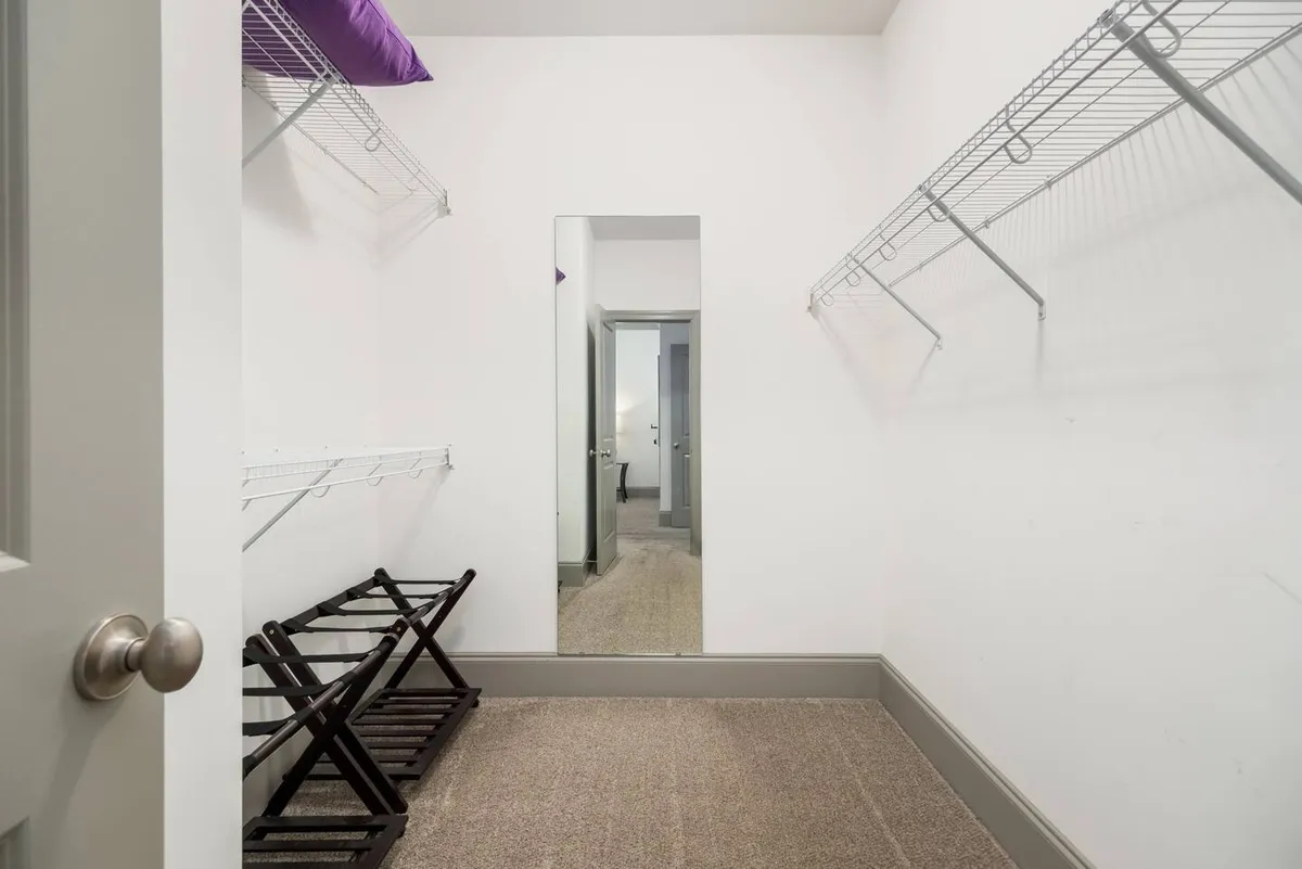 This image depicts a functional and minimalist interior space, highlighting a mirror, wire shelves, and folding stools. The setting appears organized, emphasizing storage solutions and a practical approach to preparing for daily activities.