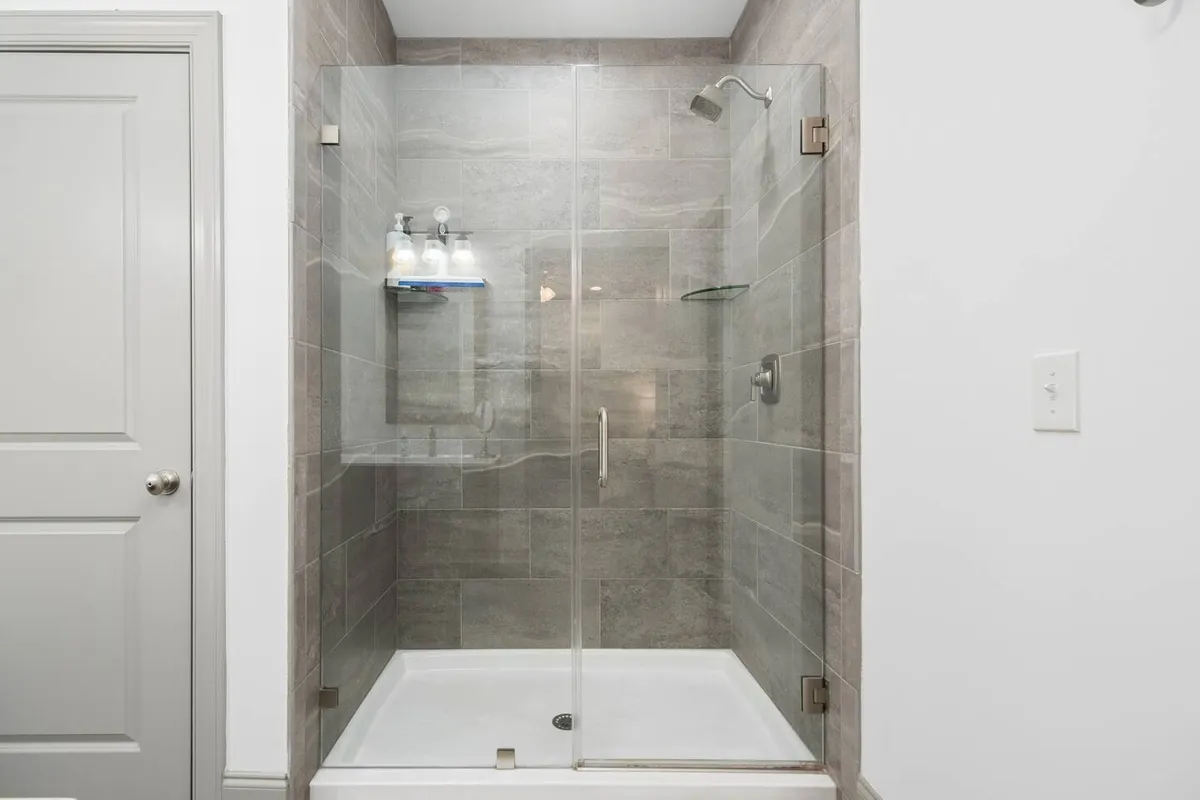 A modern bathroom with a glass shower enclosure, contemporary fixtures, and textured tile walls. The space feels inviting and tranquil, ideal for refreshing morning routines or relaxing after a long day.